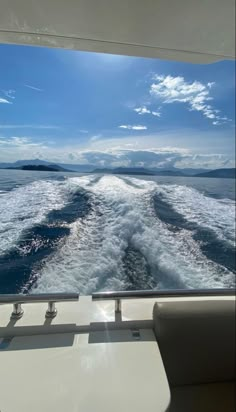 the back end of a boat traveling through the ocean on a sunny day with blue sky and clouds