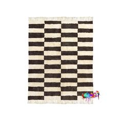 a black and white checkerboard rug with fringes on the bottom, in front of a white background