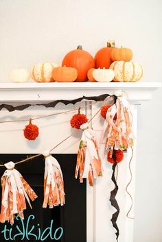 a fireplace mantel decorated for halloween with pumpkins and pom - poms