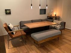 a living room filled with furniture and a wooden table surrounded by lights hanging from the ceiling