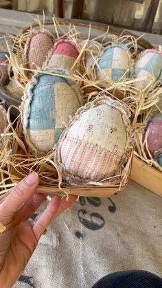 a person is holding an egg in a basket filled with hay and other decorative eggs