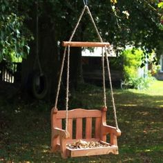 a wooden swing hanging from a tree in the grass