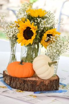 a vase filled with sunflowers and other flowers on top of a wooden slice