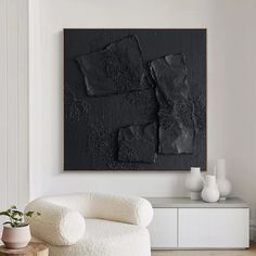 a white chair sitting in front of a black painting