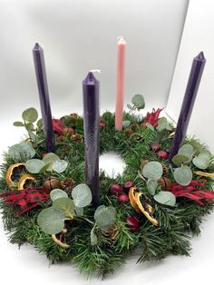 a wreath with purple candles and greenery