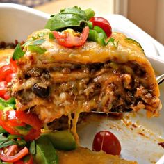 a slice of lasagna being lifted from a casserole dish with tomatoes and green peppers