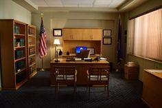 an office with two chairs and a desk in front of a book shelf filled with books