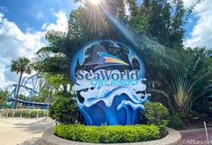 the sign for seaworld orlando is shown in front of trees and bushes on a sunny day