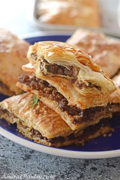 several pastries stacked on top of each other on a blue and white plate with silverware in the background