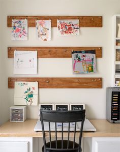 a desk with some pictures on the wall above it and a chair in front of it