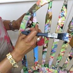 a woman is painting a colorful chair with paintbrushes