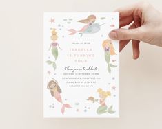 a hand holding up a card with mermaids and stars on it in front of a white background