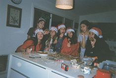 a group of women wearing christmas hats are posing for a photo in front of a kitchen counter