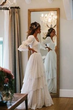 a woman is standing in front of a mirror wearing a dress with ruffles