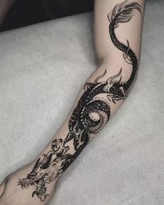 a black and white dragon tattoo on the arm