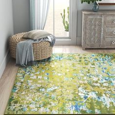 an area rug with green and blue flowers on the floor in front of a window