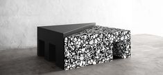 a black and white table sitting on top of a cement floor next to a wall