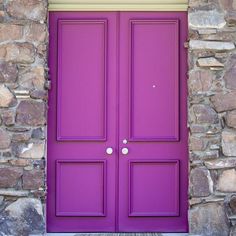 a bright purple door is in front of a stone wall