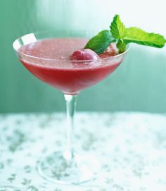 a glass filled with a drink and garnished with raspberries