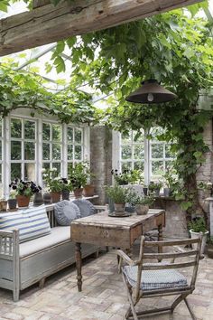 an outdoor room with lots of plants and furniture