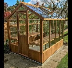 a small wooden greenhouse built into the side of a house