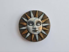 a ceramic sun face on a white wall