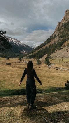 a woman standing on top of a lush green hillside