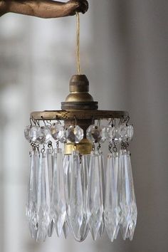 a chandelier hanging from a ceiling with crystal drops on the bottom and brass fittings