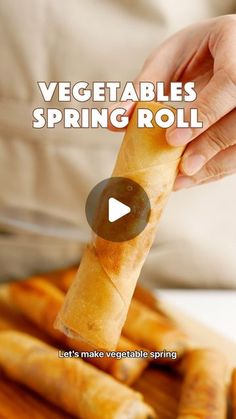 a person holding a vegetable spring roll in front of some breadsticks on a cutting board