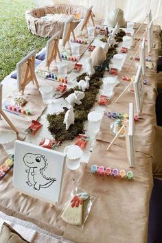 a long table covered in lots of plates and bowls with plants growing out of them