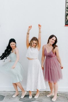 three women standing next to each other with their arms in the air