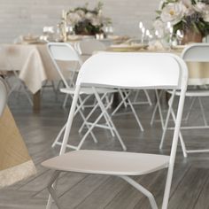 a white folding chair sitting on top of a hard wood floor next to a table