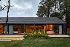 a modern house with large windows and sliding glass doors on the outside, surrounded by lush greenery