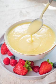 a white bowl filled with cheese and strawberries on top of a plate next to a spoon