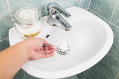 a person's hand is holding the faucet in front of a bathroom sink