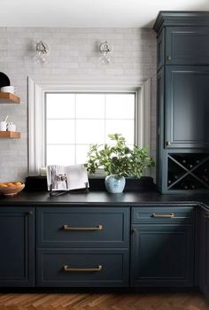 a kitchen with black cabinets and white brick walls, wood flooring and open shelves