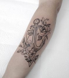 a black and white anchor with flowers on the side of his arm, tattoo style