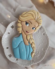 a close up of a cake on a plate with a frozen princess figure in the middle