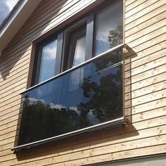 a wooden house with a large window on the side and sky in the back ground