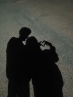 two people standing next to each other with their shadows on the ground in front of them