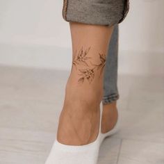 a woman's foot with a tattoo on her left leg and flowers on the ankle