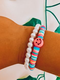 a woman's arm with two bracelets and a smiley face beaded on it