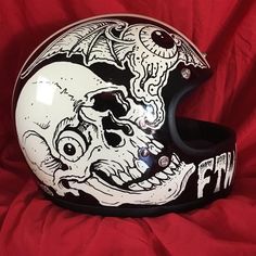 a helmet with an image of a skull on the front and side, sitting on a red sheet