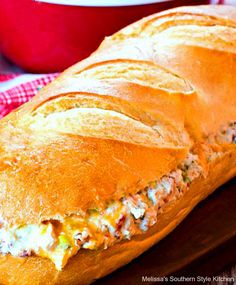 a close up of a sandwich on a wooden board with a bowl in the background