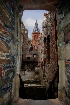 an alley way with brick buildings and a steeple in the background