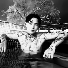 a man with tattoos sitting in a pool