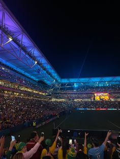 a crowd of people at a tennis match taking pictures with their cell phones in the air