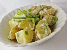 a white bowl filled with potatoes and green onions