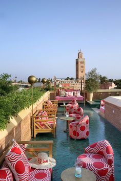 red and white chairs sitting on top of a pool next to a tall clock tower