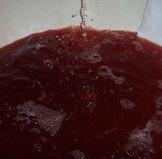 red liquid is being poured into a white bowl